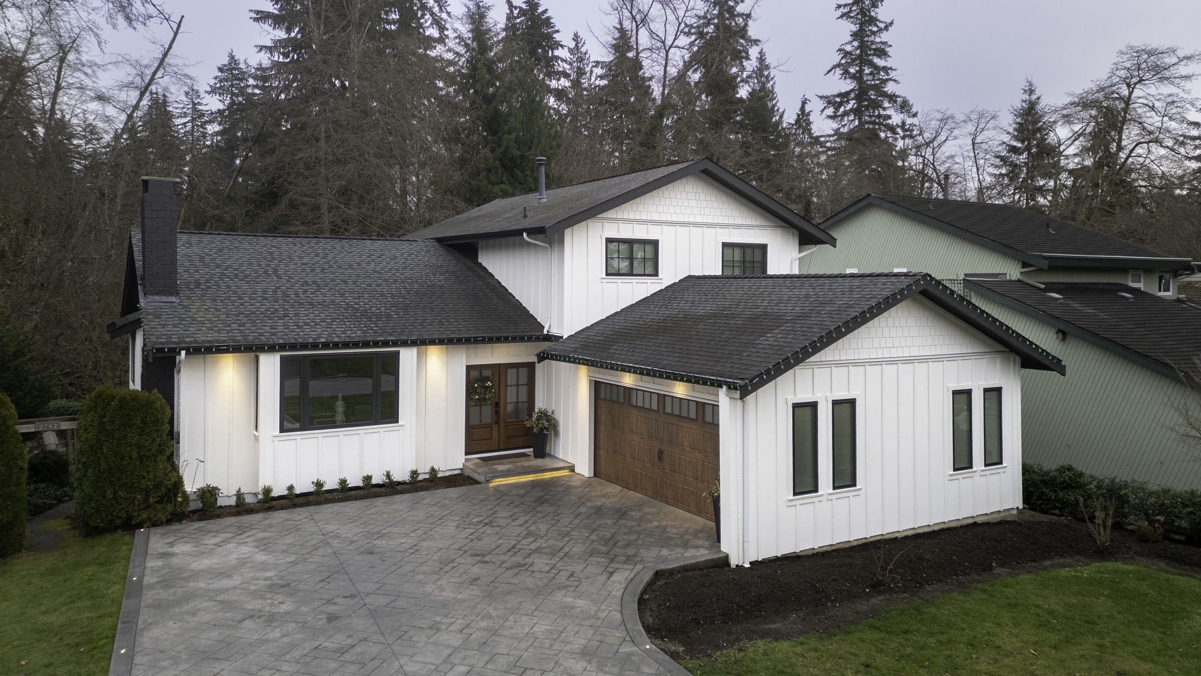 Twilight aerial drone photo of a modern farmhouse exterior and stamped-concrete driveway
